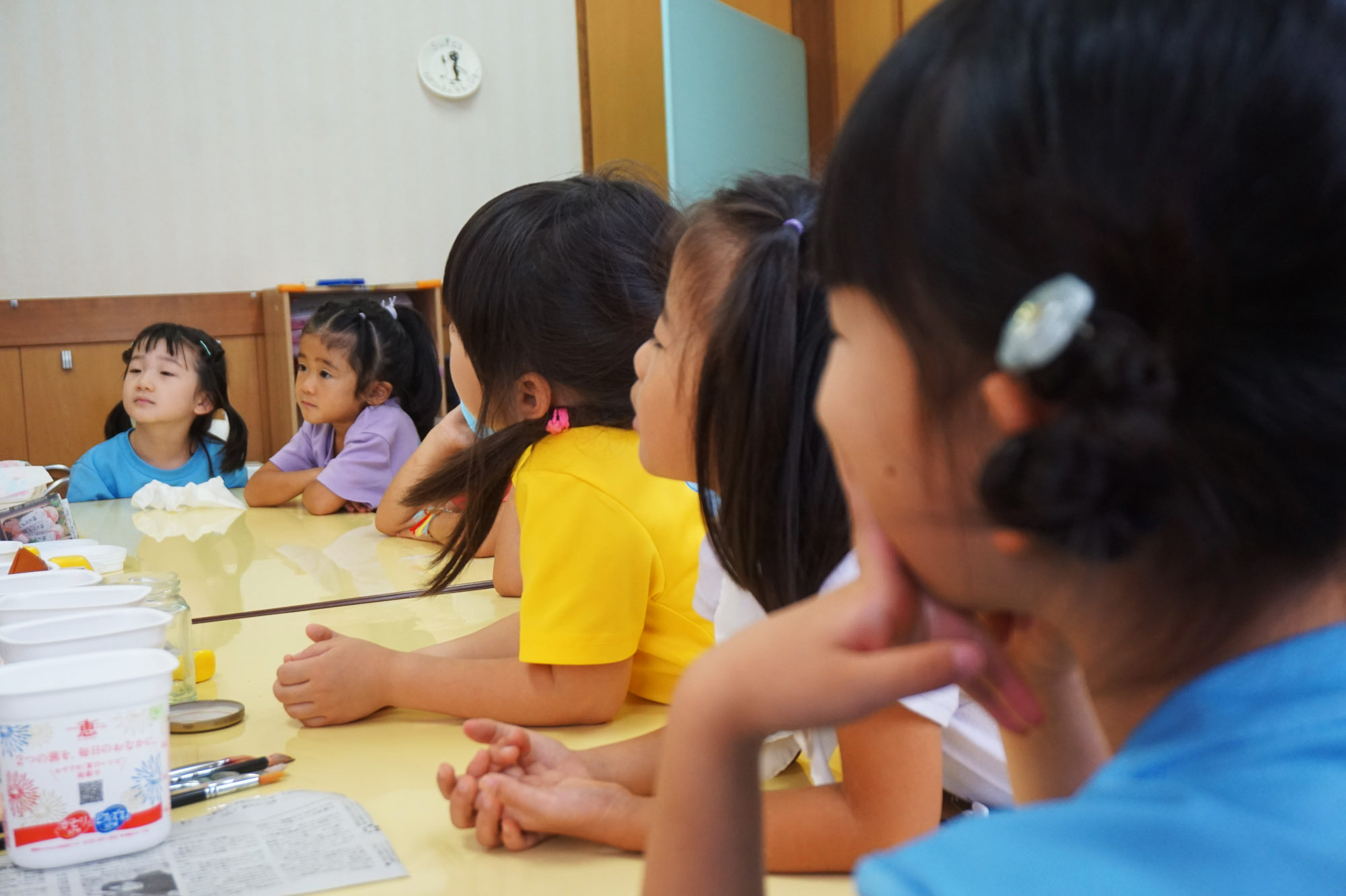 工作の授業で先生の説明を真剣なまなざしで聞いている幼稚園児